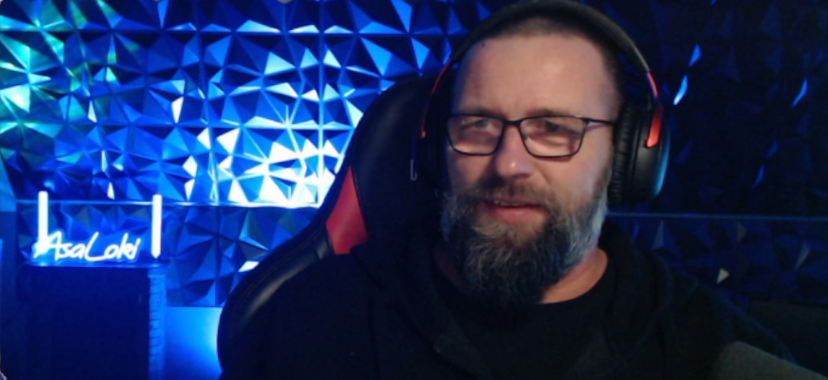 AsaLoki im Stream vor blau beleuchteter Gaming-Wand und AsaLoki-Leuchtschild